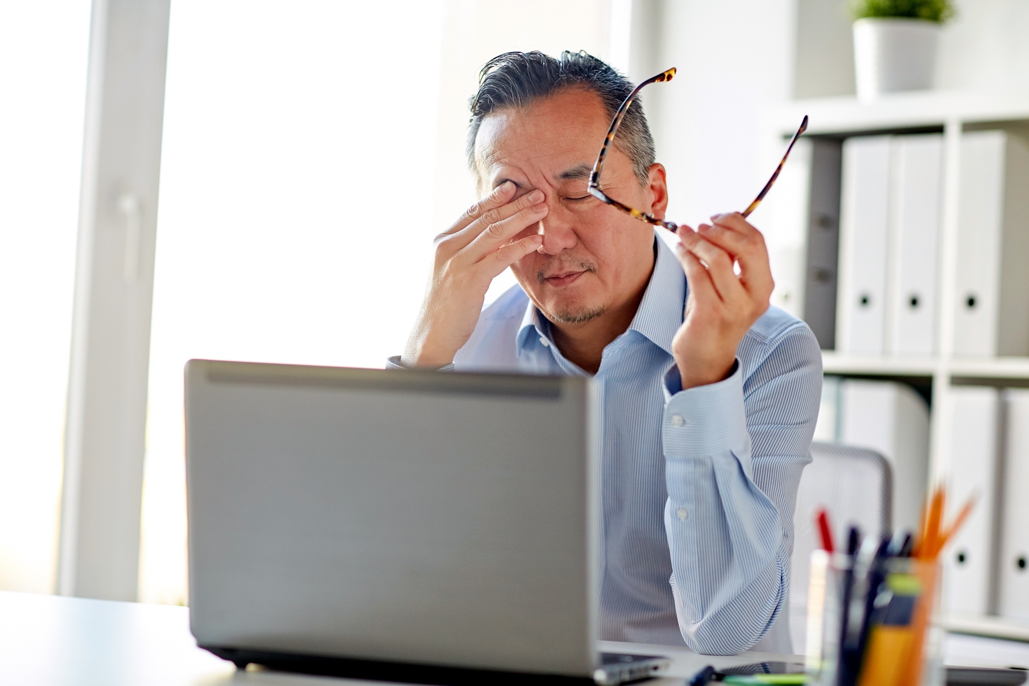 tired businessman with glasses at laptop in office