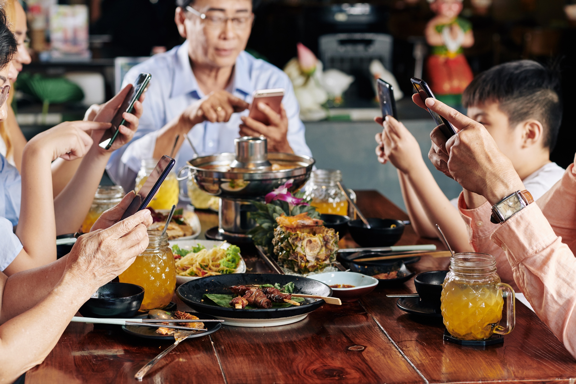 Family members with smartphones spending time on social media instead of talking during family dinner