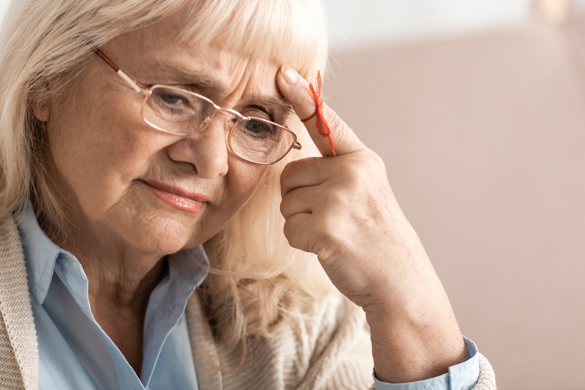 pensive senior woman with alzheimers disease string human finger reminder